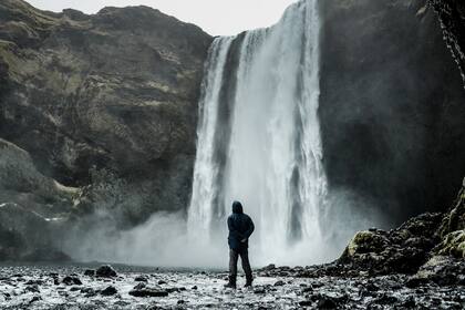 Un hombre en la cascada skogafoss en Islandia