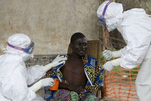 Un hombre en Sierra Leona enfermo de ébola recibe cuidados por personal de la OMS