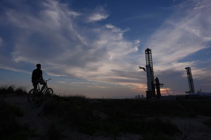Un hombre en una bicicleta observa el mega cohete Starship de SpaceX en la plataforma de lanzamiento en Boca Chica, Texas (AP Foto/Eric Gay)
