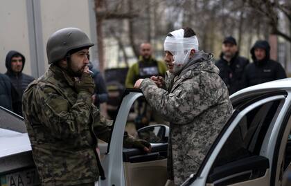 Un hombre herido habla con un soldado, a la izquierda, tras ser evacuado de Irpin, en las afueras de Kiev, Ucrania, el miércoles 30 de marzo de 2022.