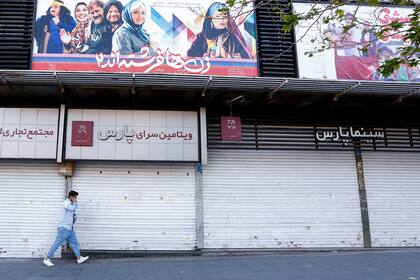 Un hombre iraní con una máscara facial pasa frente a un cine cerrado en la capital, Teherán, el 29 de marzo de 2021