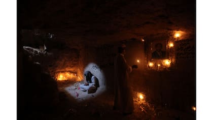 Un hombre lee versos del Corán en la tumba de un pariente.