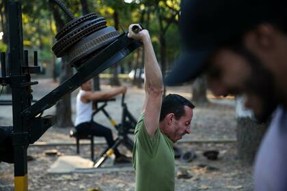 Un hombre levanta piezas de repuesto para autos y camiones en un improvisado gimnasio en el parque público Los Caobos en Caracas