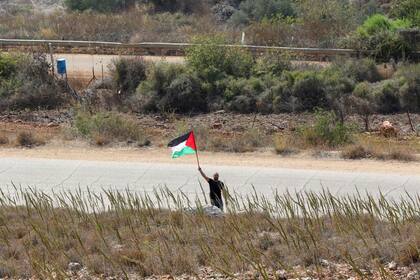 Un hombre libanés ondea una bandera palestina en solidaridad con el pueblo palestino cerca de un punto fronterizo en la llanura de Khiyam en Líbano, frente a la ciudad israelí del norte de Metulla el 9 de octubre de 2023. 