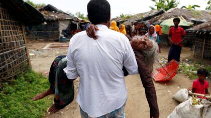 Un hombre lleva a una mujer refugiada de Rohingya desde la orilla luego de cruzar la frontera de Bangladesh-Myanmar en un barco a través de la bahía de Bengala