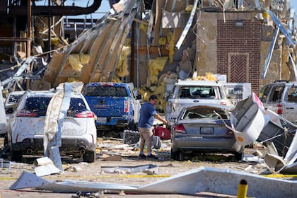 Un hombre mira a un auto dañado después de que un tornado pasara el día anterior.