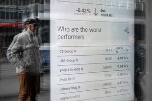 Un hombre mira un tablero de mercado en la sede del gigante bancario suizo UBS en Zúrich el 20 de marzo de 2023. (Fabrice COFFRINI / AFP)