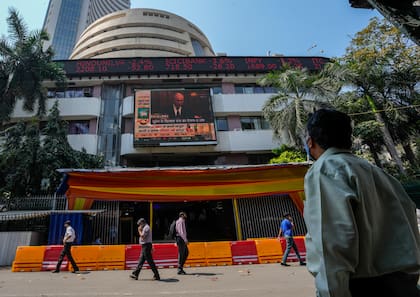 Un hombre mira una pantalla en la que se ve una noticia sobre el presidente de Rusia, Vladimir Putin, en la fachada de la Bolsa de Bombay, en Mumbai, India, el jueves 24 de febrero de 2022.