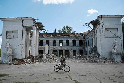 Un hombre monta su bicicleta más allá de un edificio destruido en Druzhkivka, región de Donetsk, el 15 de agosto de 2025 en medio de la invasión rusa de Ucrania