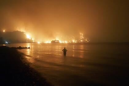 Un hombre observa un incendio cerca de la playa de Kochyli cerca del pueblo de Limni, en la isla de Evia, a unos 160 kilómetros (100 millas) al norte de Atenas, la noche del viernes 6 de agosto de 2021. (AP Foto/Thodoris Nikolaou)