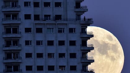 Un hombre parece observar la superluna desde el balcón de un edificio en Madrid