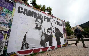 Un hombre pasa frente a un cartel de campaña del candidato presidencial Gustavo Petro y su compañera de fórmula Francia Márquez, con la coalición Pacto Histórico, en Bogotá