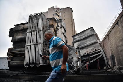 Un hombre pasa frente a una subestación eléctrica dañada en Caracas, donde se produjeron explosiones de causa desconocida durante las primeras horas de la madrugada.
