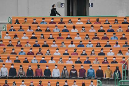 Un hombre pasa junto a pancartas que representan a los espectadores en las gradas antes del nuevo juego de apertura de la temporada de béisbol de Corea del Sur