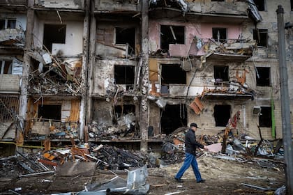Un hombre pasa por delante de un edificio dañado por el impacto de un proyectil, en Kiev, Ucrania.