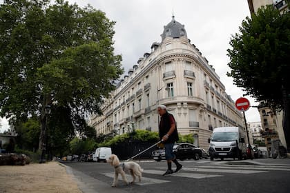 Un hombre pasea al perro ante un edificio de departamentos propiedad de Jeffrey Epstein en París