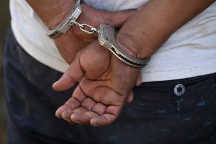 Un hombre permanece esposado tras ser detenido por la policía durante una operación contra pandilleros en Soyapango, El Salvador, el 3 de diciembre