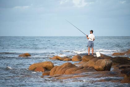 Un hombre pesca entre las rocas.