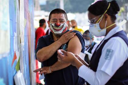 Un hombre porta una mascarilla mientras se prepara para recibir la vacuna contra la influenza en medio de la pandemia
