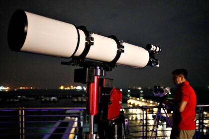 Un hombre prepara su telescopio en la Marina South Pier en Singapur