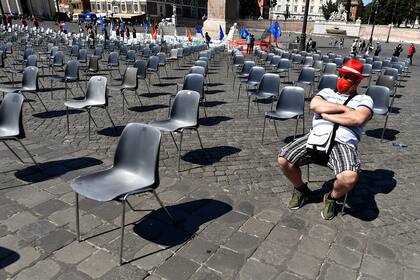 Un hombre que lleva una mascarilla de la Confederación General de Trabajadores de Italia (CGIL) se sienta mientras espera el inicio de una manifestación nacional de trabajadores metalúrgicos en la céntrica Piazza del Popolo de Roma, para protestar contra el empeoramiento de la crisis por el coronavi