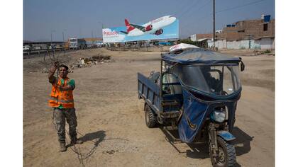 Un hombre recoge cables para la reventa, junto con otros objetos reciclables, a lo largo de la Carretera Panamericana en el lado sur de Lima