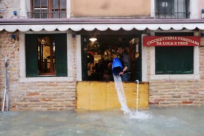 Un hombre retira agua de su negocio inundado durante el período de temporada alta en Venecia, Italia, 15 de noviembre de 2019