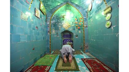 Un hombre reza el interior del mausoleo del Imam Mahdi en el cementerio de Wadi al-Salam
