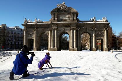 Un hombre saca fotografías a su perro frente a la Puerta de Alcalá, en Madrid