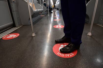 Un hombre se para en un círculo rojo, con el objetivo de mantener la distancia entre los viajeros en una línea de subte en Milán, el 28 de abril de 2020
