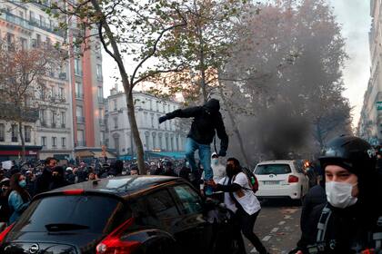 Un hombre se sube a un automóvil en París durante la protesta contra el proyecto de ley de seguridad global,