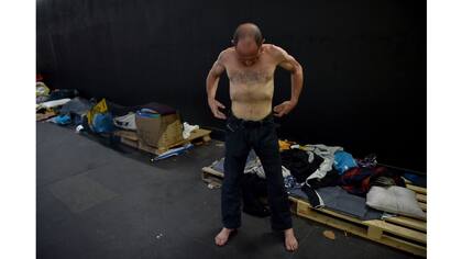 Un hombre sin hogar se viste en un refugio improvisado para los desamparados en Sidney que ofrece el acceso a comida y abrigo apenas a metros del banco central de Australia