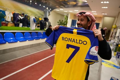Un hombre sostiene camisetas de Cristiano Ronaldo en la tienda del club de fútbol Al Nassr en Riyadh, Arabia Saudita