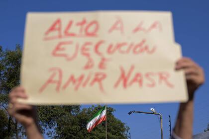 Un hombre sostiene un cartel durante una protesta contra la ejecución del futbolista iraní Amir Nasr-Azadani -condenado a muerte en el marco de las protestas tras la muerte de Mahsa Amini- frente a la embajada de Irán en Ciudad de México el 19 de diciembre de 2022.