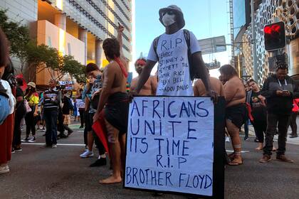 Un hombre sostiene un cartel con miles de personas que marchaban durante una protesta de Black Lives Matter en Brisbane, Australia