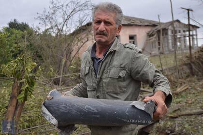 Un hombre sostiene un fragmento de munición tras lo que se dice fue un ataque azerí durante los enfrentamientos entre separatistas armenios y Azerbaiyán en la región de Nagorno-Karabaj