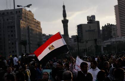 Un hombre sostiene una bandera egipcia mientras el sol se pone en una protesta masiva antigubernamental en la Plaza Tahrir el 30 de enero de 2011 en El Cairo, durante la llamada "primavera árabe"