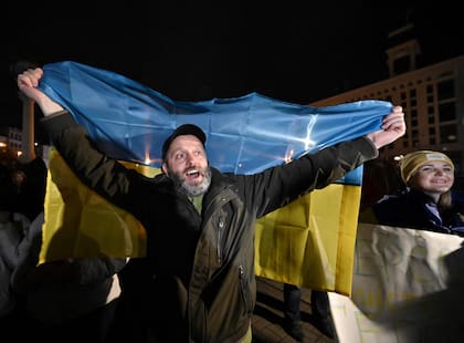 Un hombre sostiene una bandera ucraniana mientras la gente se reúne en la plaza Maidan para celebrar la liberación de Kherson, en Kiev el 11 de noviembre de 2022, en medio de la invasión rusa de Ucrania.