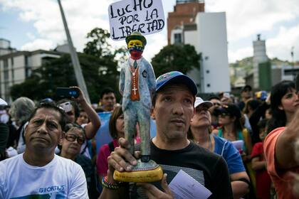 Un hombre sostiene una estatuilla del santo popular venezolano José Gregorio Hernández con un cartel que dice "Lucho por la libertad", mientras los miembros de la oposición se reúnen para proponer leyes de amnistía para la policía y los militares, en el barrio Las Mercedes de Caracas