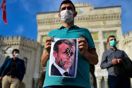 Un hombre sostiene una foto de Macron con una huella de zapato durante una manifestación contra los comentarios del presidente francés sobre las caricaturas del Profeta Muhammad, en Estambul, el 25 de octubre de 2020