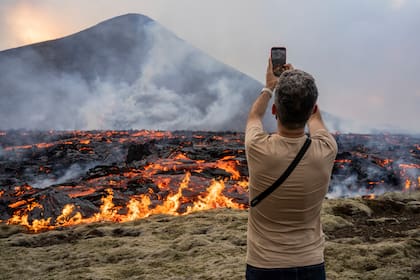 Un hombre toma fotografías mientras la lava emerge de una fisura del volcán Fagradalsfjall cerca de la montaña Litli-Hrútur
