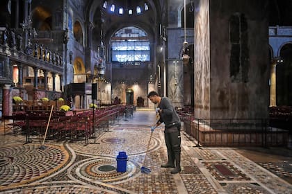 Un hombre trapea el piso de la Basílica de San Marcos inundada después de un excepcional nivel de agua durante la marea alta