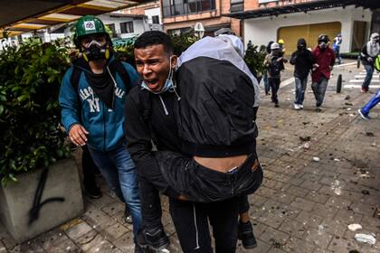 Un hombre traslada a un herido en Medellín