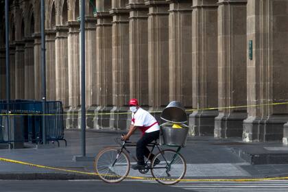 Un hombre usa un tapabocas mientras monta una bicicleta en el centro histórico de la Ciudad de México, el 11 de julio pasado