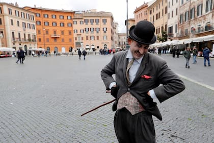 Un hombre vestido como Charlie Chaplin posa para una fotografía en una Piazza Navona casi vacía, que generalmente estaría llena de turistas, en Roma, Italia, el 2 de marzo de 2020