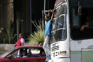 Un hombre viaja en el frente de un colectivo, tras el apagón en Caracas