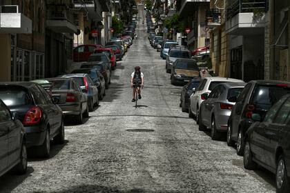 Un hombre viaje en su bicicleta por una calle desierta del centro de Atenas, en Grecia, el 20 de abril de 2020, en medio de la pandemia de coronavirus