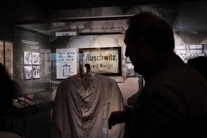Un hombre visita la muestra y observa las ropas que utilizaban los prisioneros en el campo de concentración