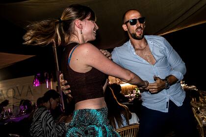 Un hombre y una mujer bailan en la arena en un restaurante al aire libre de una playa en Fregene, cerca de Roma, el 14 de agosto de 2020