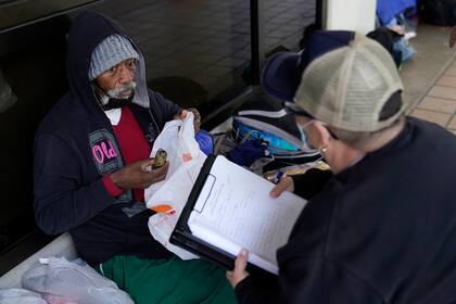 Un homeless en el centro de Miami es asistido por un trabajador municipal ante la ola de frío (AP Photo/Lynne Sladky)